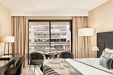 A hotel room with a sliding glass door leading to a balcony