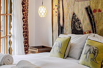 A bed with elephant pillows and a tapestry on the wall