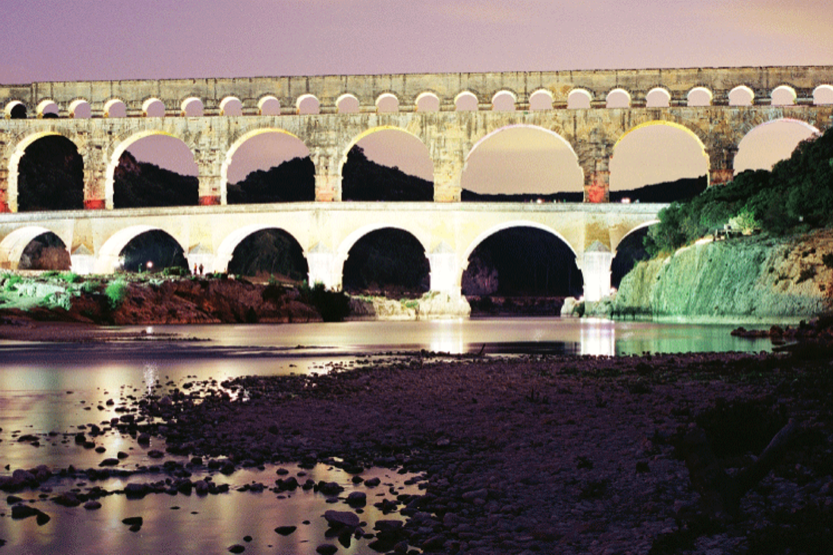 a roman aqueduct ruin at night lit up