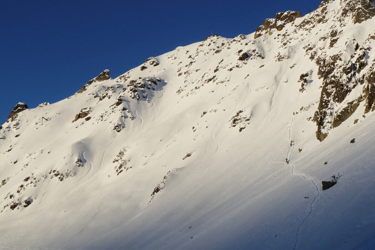 a view of a face with a small trail of riders climbing up