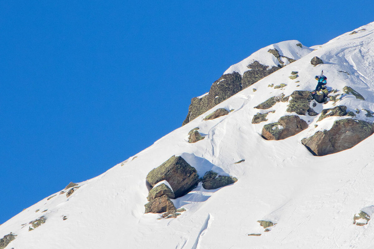 Snowboarder dropping a cliff and grabbing