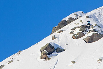 Snowboarder dropping a cliff and grabbing