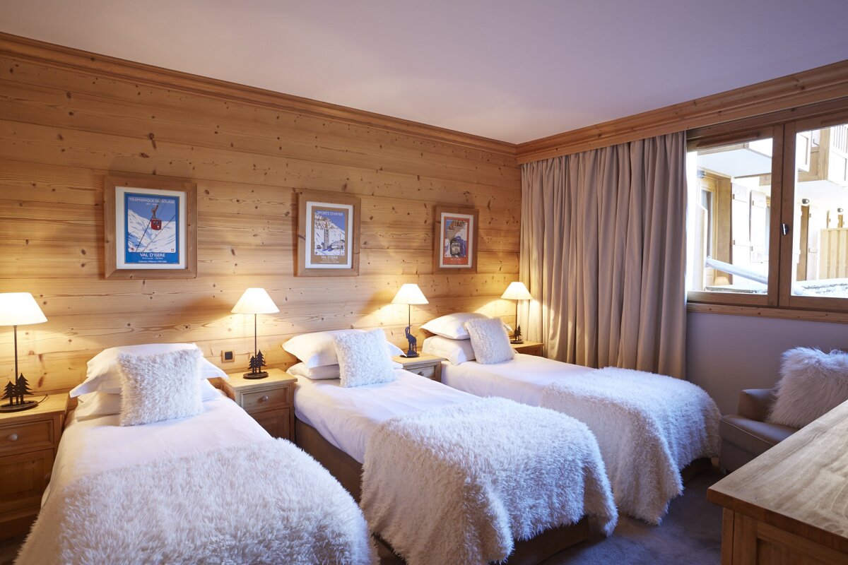 A hotel room with three beds and a poster on the wall that says 