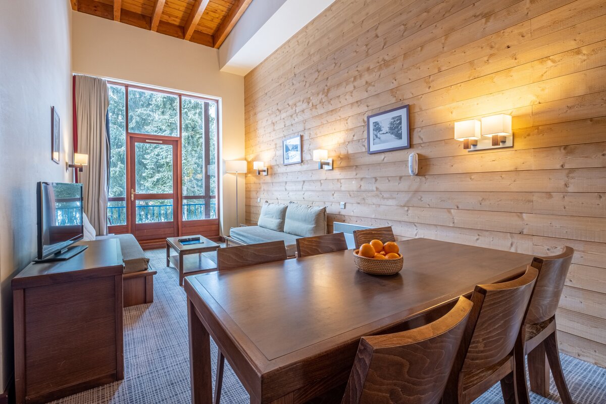 A living room with wood paneling and a table and chairs