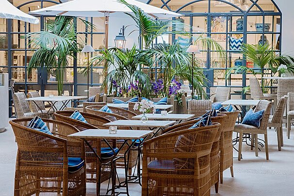 A restaurant with wicker chairs and tables with umbrellas