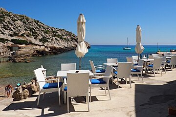 tables and chairs on a restaurant terrace overlooking the sea