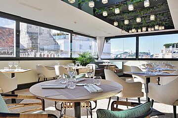 A restaurant with tables and chairs and a view of the city