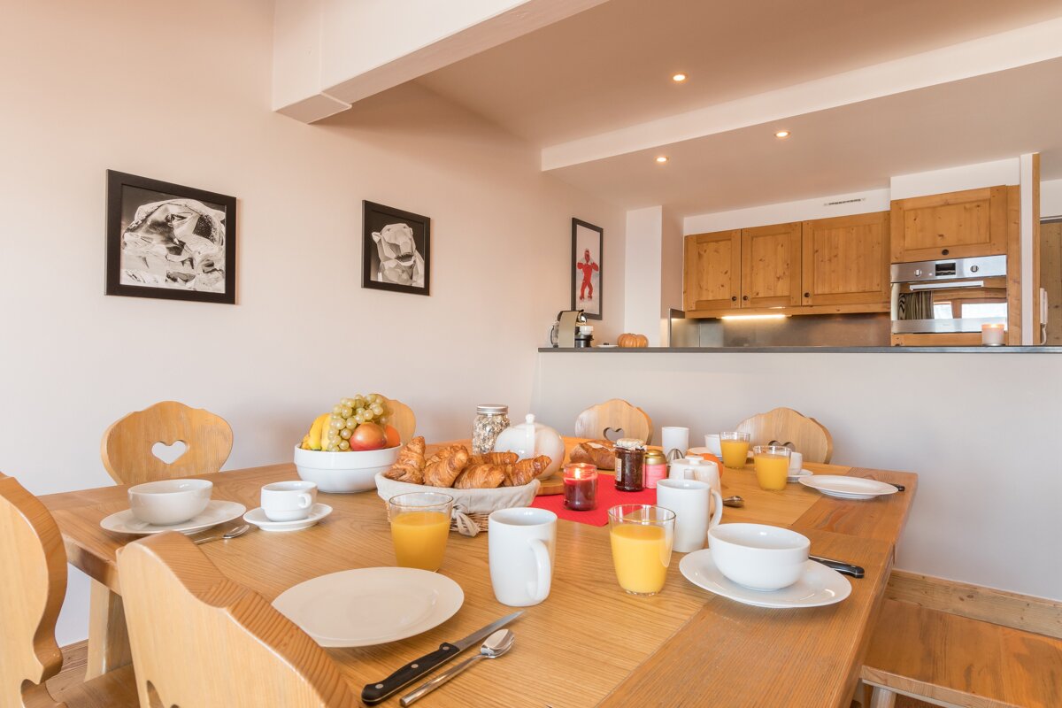 A dining room table with a bowl of croissants on it