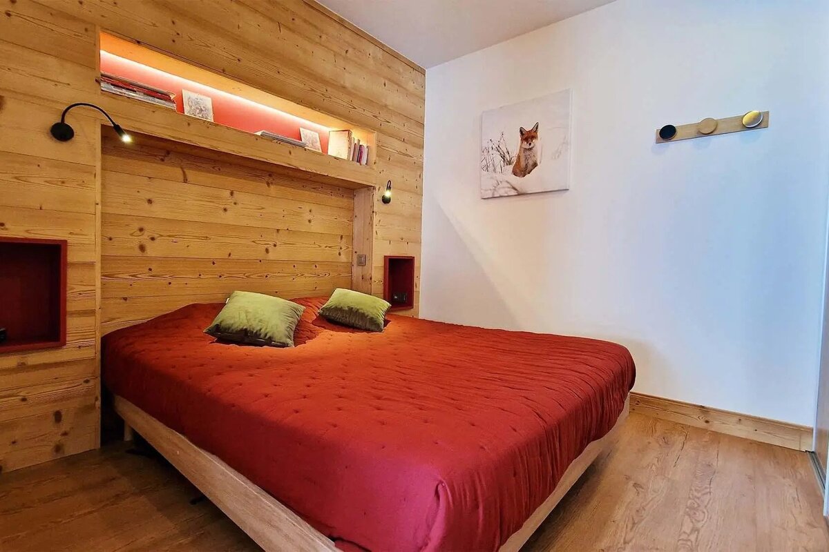 A bedroom with a red bed and a picture of a fox on the wall