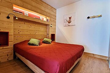 A bedroom with a red bed and a picture of a fox on the wall