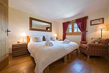 A bedroom with two beds a chair and a mirror