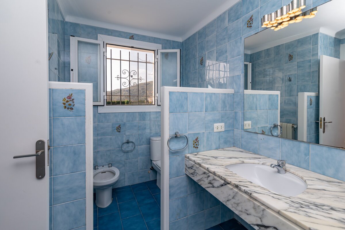 A bathroom with blue tiles and a sink