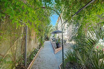 A narrow path leading to a patio with umbrellas