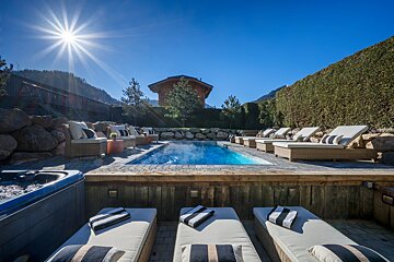 A swimming pool surrounded by lounge chairs and a hot tub
