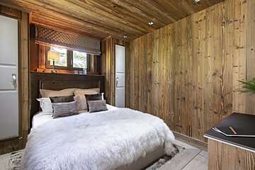 A bedroom with wooden walls and a bed