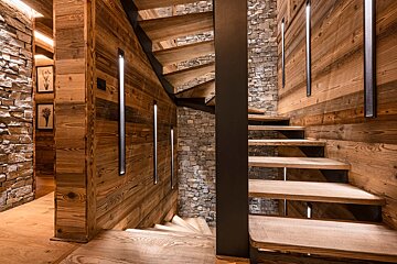 A wooden staircase with a stone wall behind it