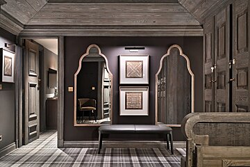 A hallway with a bench and two mirrors on the wall