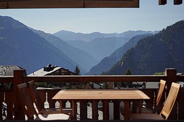 A view of the mountains from a balcony with a table and chairs