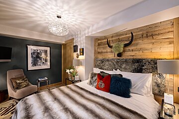 A bedroom with a bed a chair and a picture on the wall