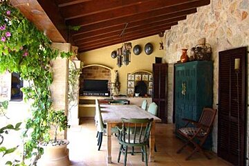 There is a table and chairs on the porch of a house