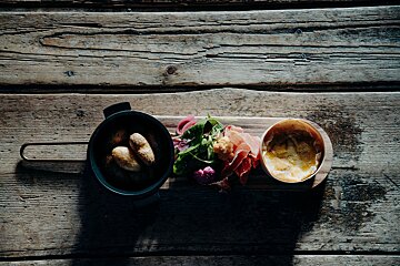 A wooden table with a bowl of potatoes and a bowl of food