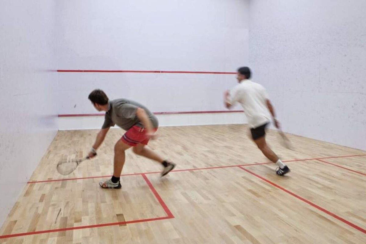 two men playing squash indoors