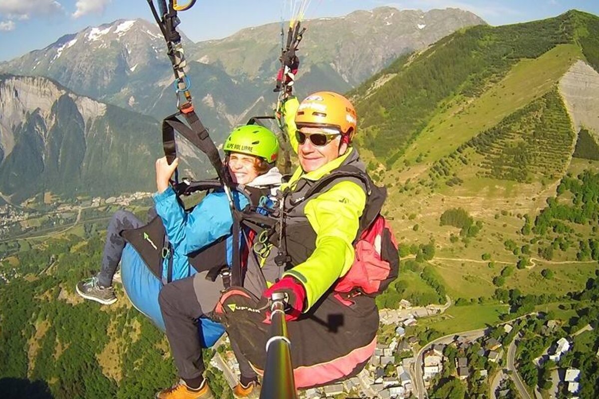 A man and a woman are parasailing over a mountain range