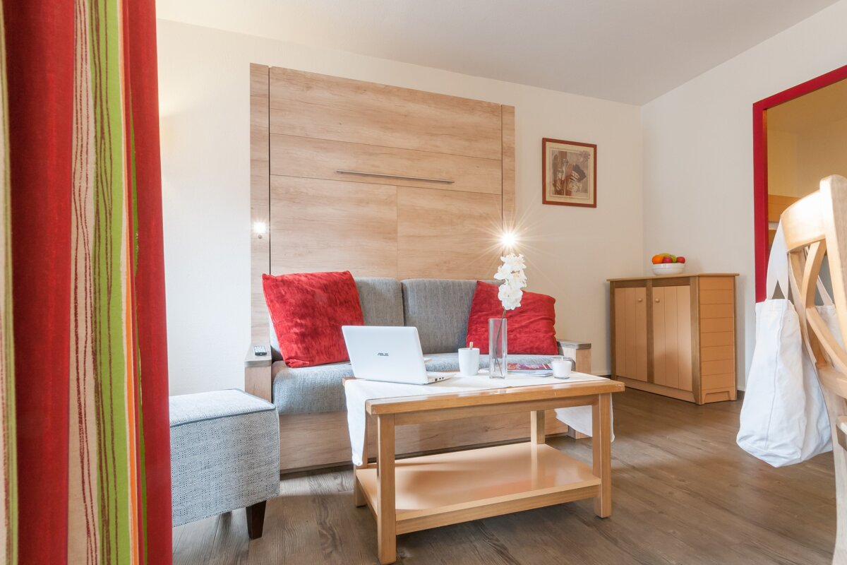 A living room with a couch and a table with a laptop on it