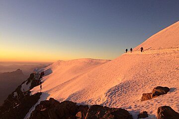A group of people are walking up a snowy mountain