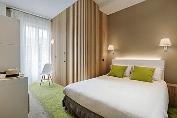 A bedroom with a white bed and green pillows