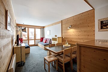 A living room with wood paneling and a table and chairs
