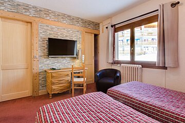 A bedroom with two beds and a flat screen tv
