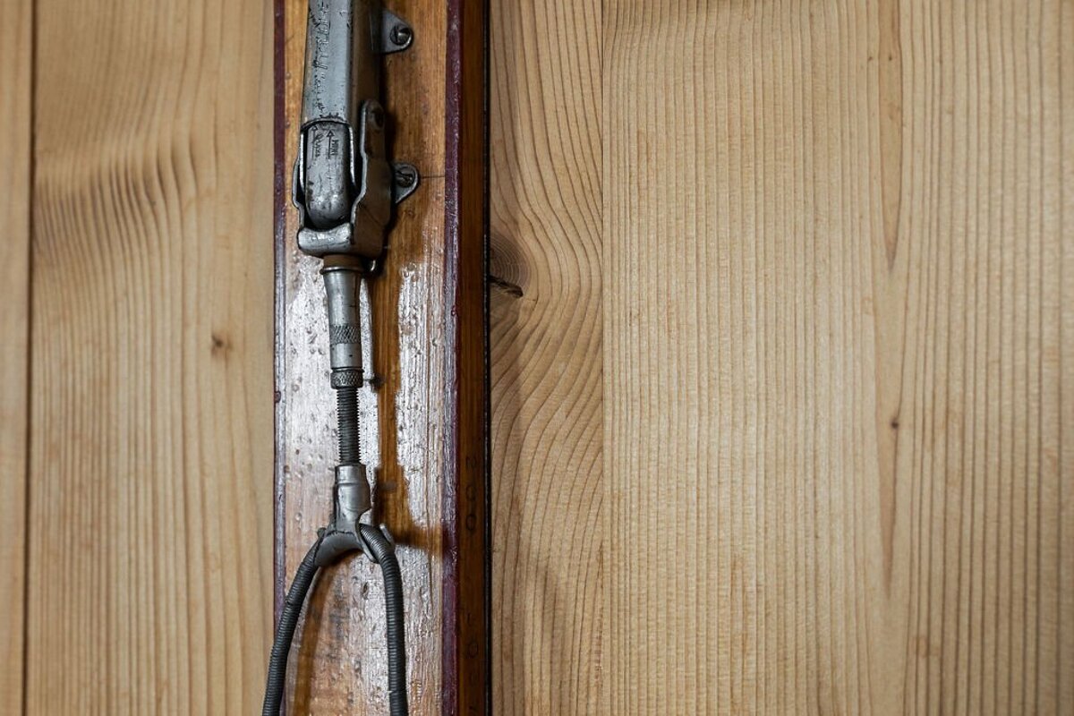 A close up of a piece of metal on a wooden wall