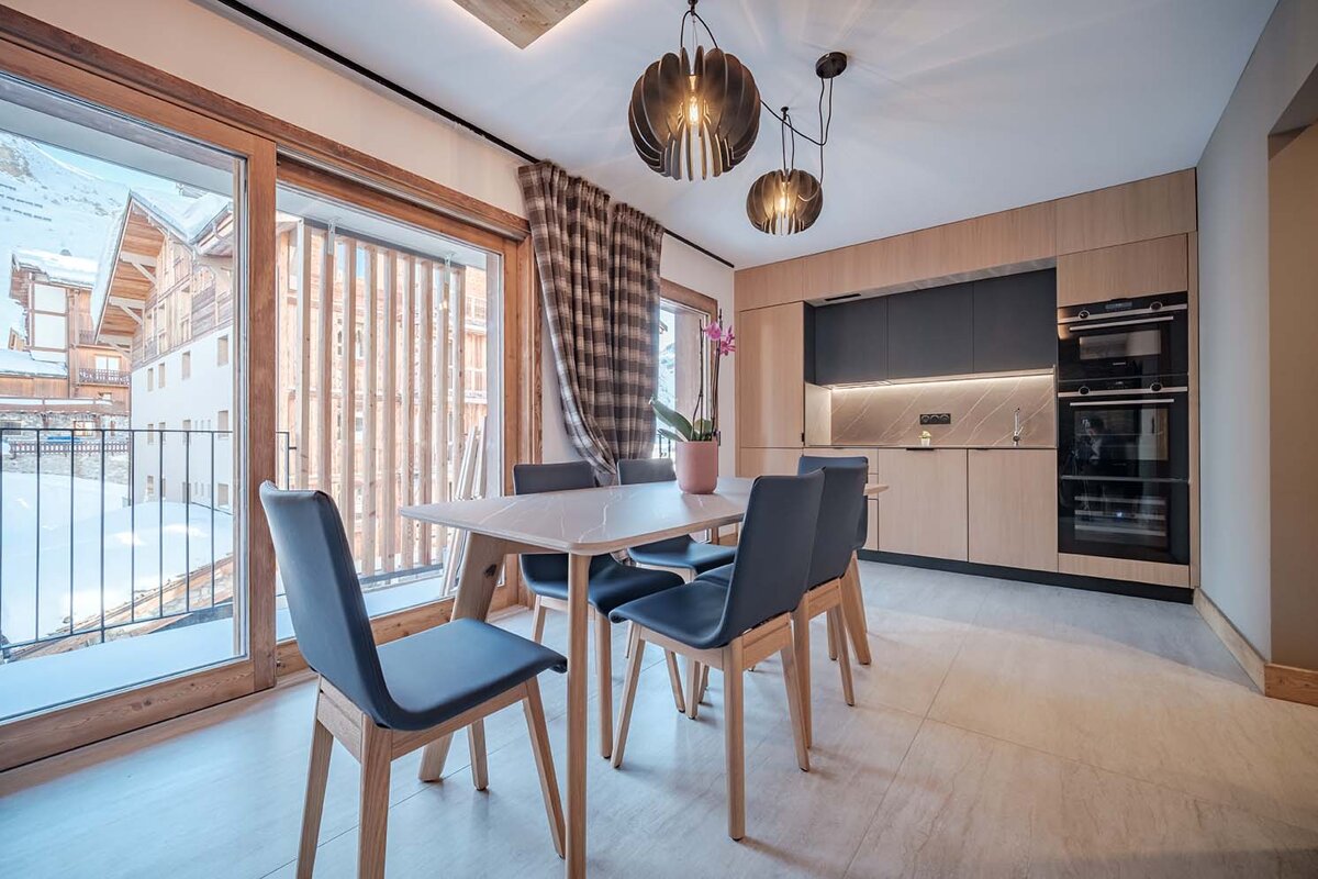 A kitchen with a table and chairs and a balcony