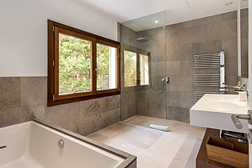 A bathroom with two sinks and a walk in shower