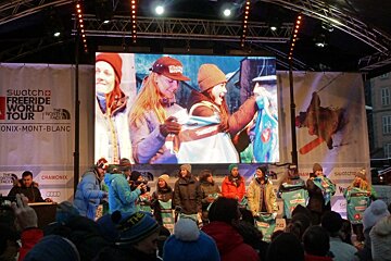 A group of people standing in front of a large screen that says swatch freeride world tour