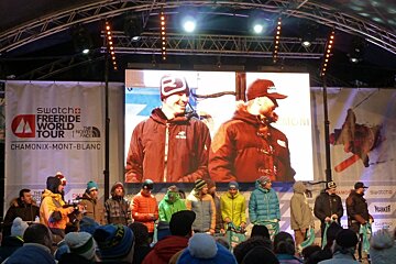 A group of people standing in front of a swatcha freeride world tour sign