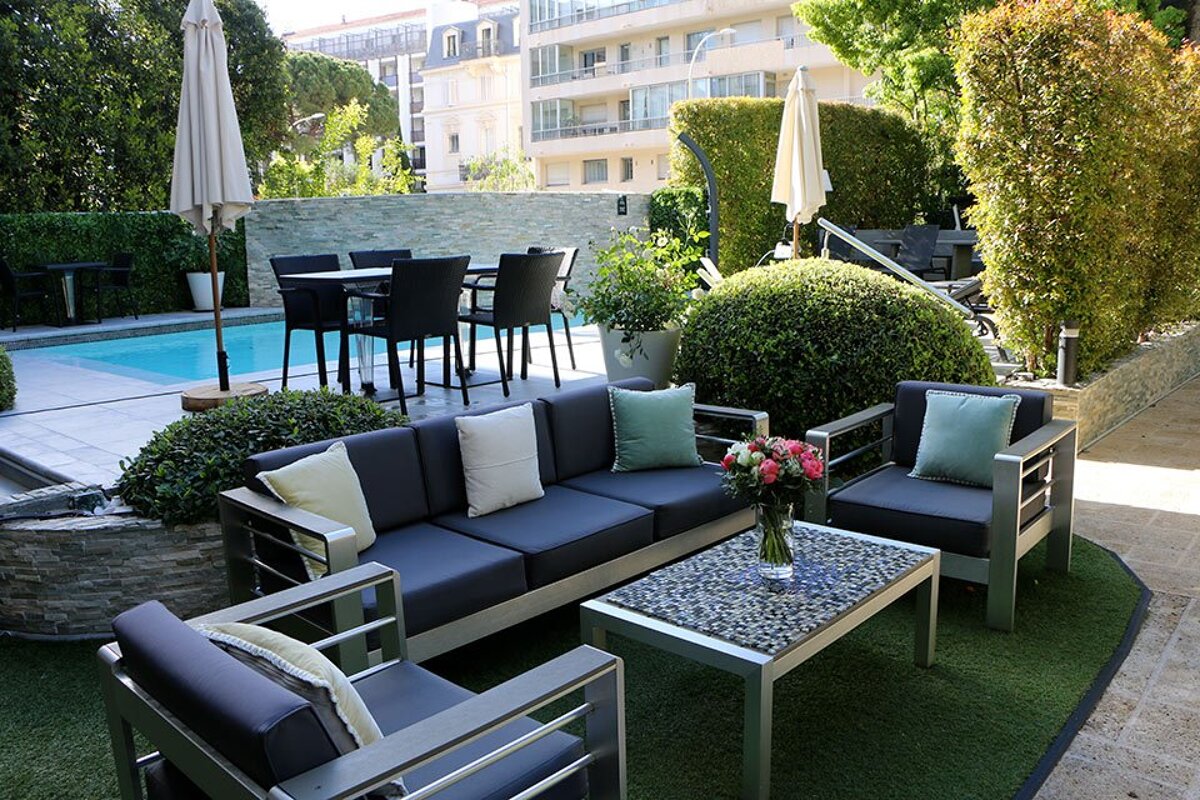 A patio with a couch and chairs next to a pool