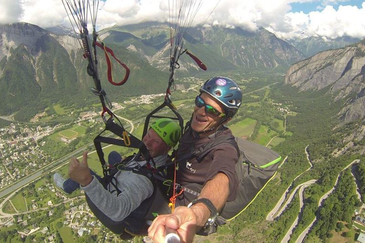 A man wearing a helmet and sunglasses is flying a parachute