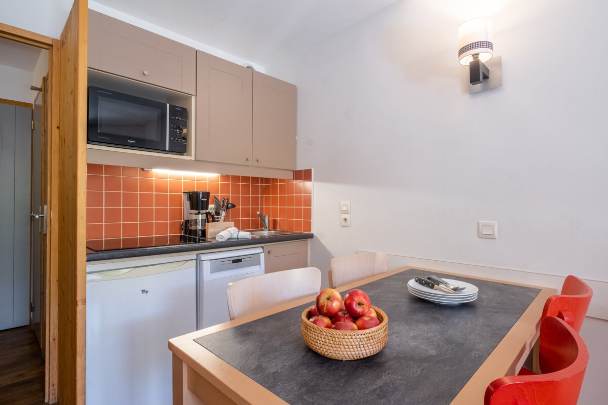 A kitchen with a microwave and a table with apples on it