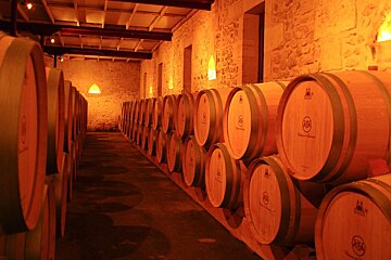 A row of wooden barrels in a wine cellar with the word chateau on the front