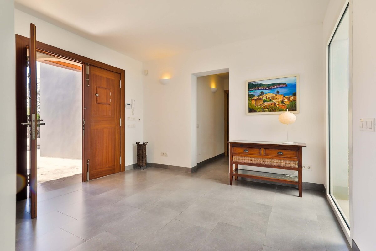 A hallway with a wooden door and a painting on the wall