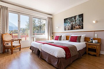 A hotel room with two beds and a picture of a deer on the wall