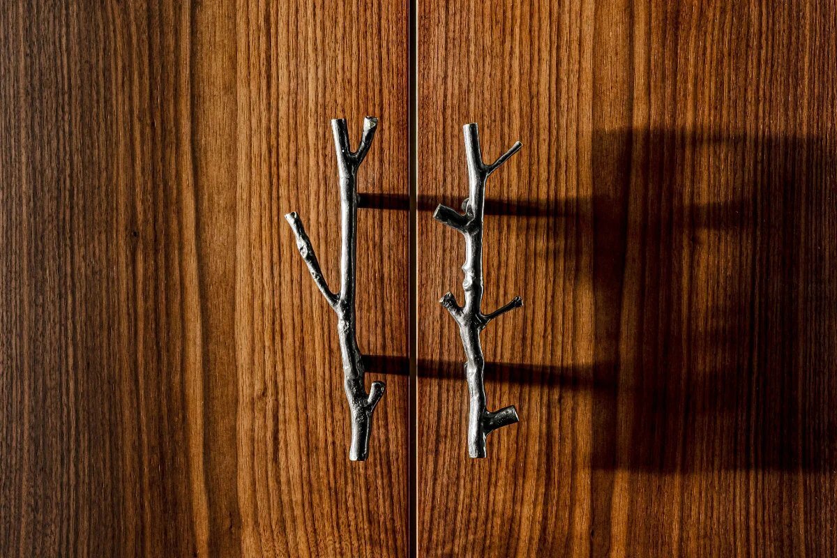 A pair of metal handles that look like branches on a wooden door