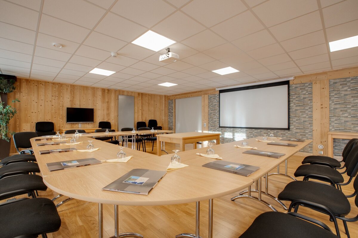 A conference room with tables and chairs and a projector screen
