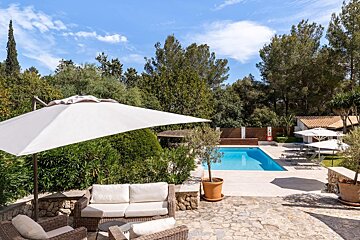 A white umbrella sits in front of a swimming pool