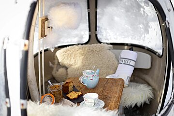 A tea set sits on a wooden table next to a towel that says un gout