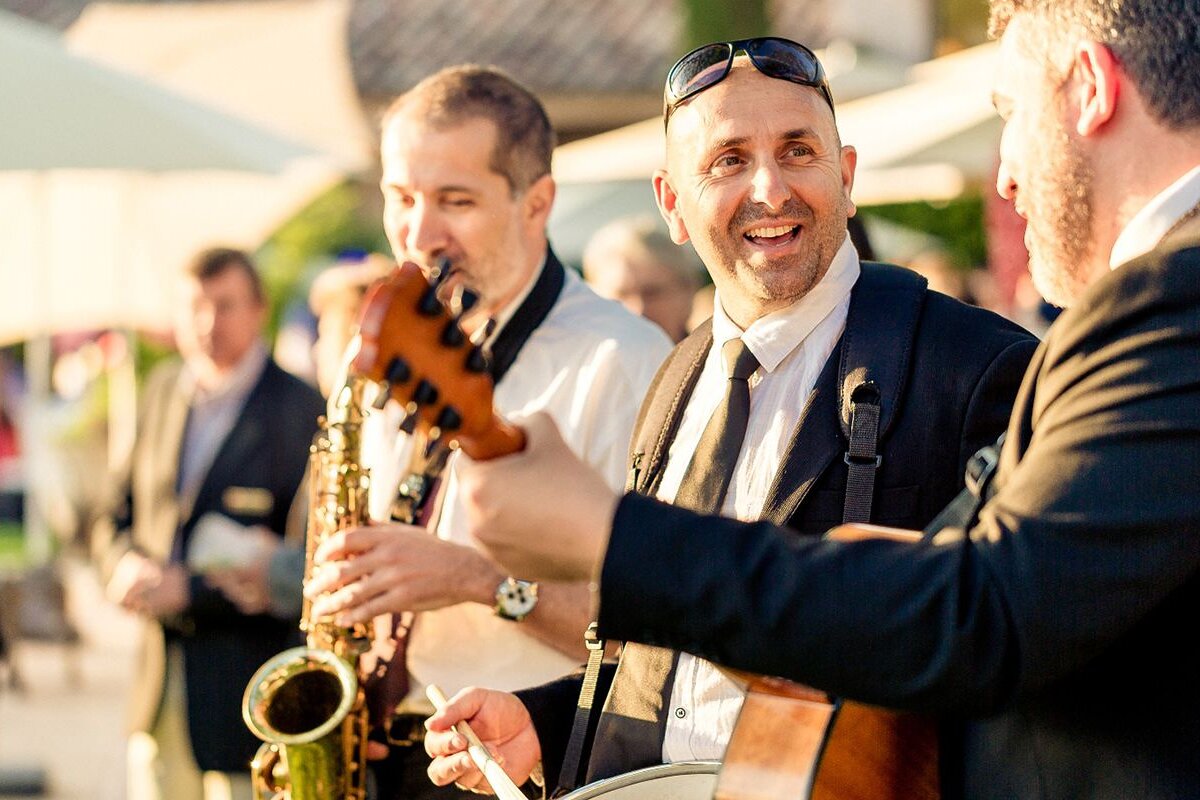 A man playing a guitar while another man plays a saxophone