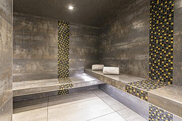 Two towels sit on a bench in a tiled room