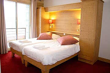 A hotel room with two beds and a window